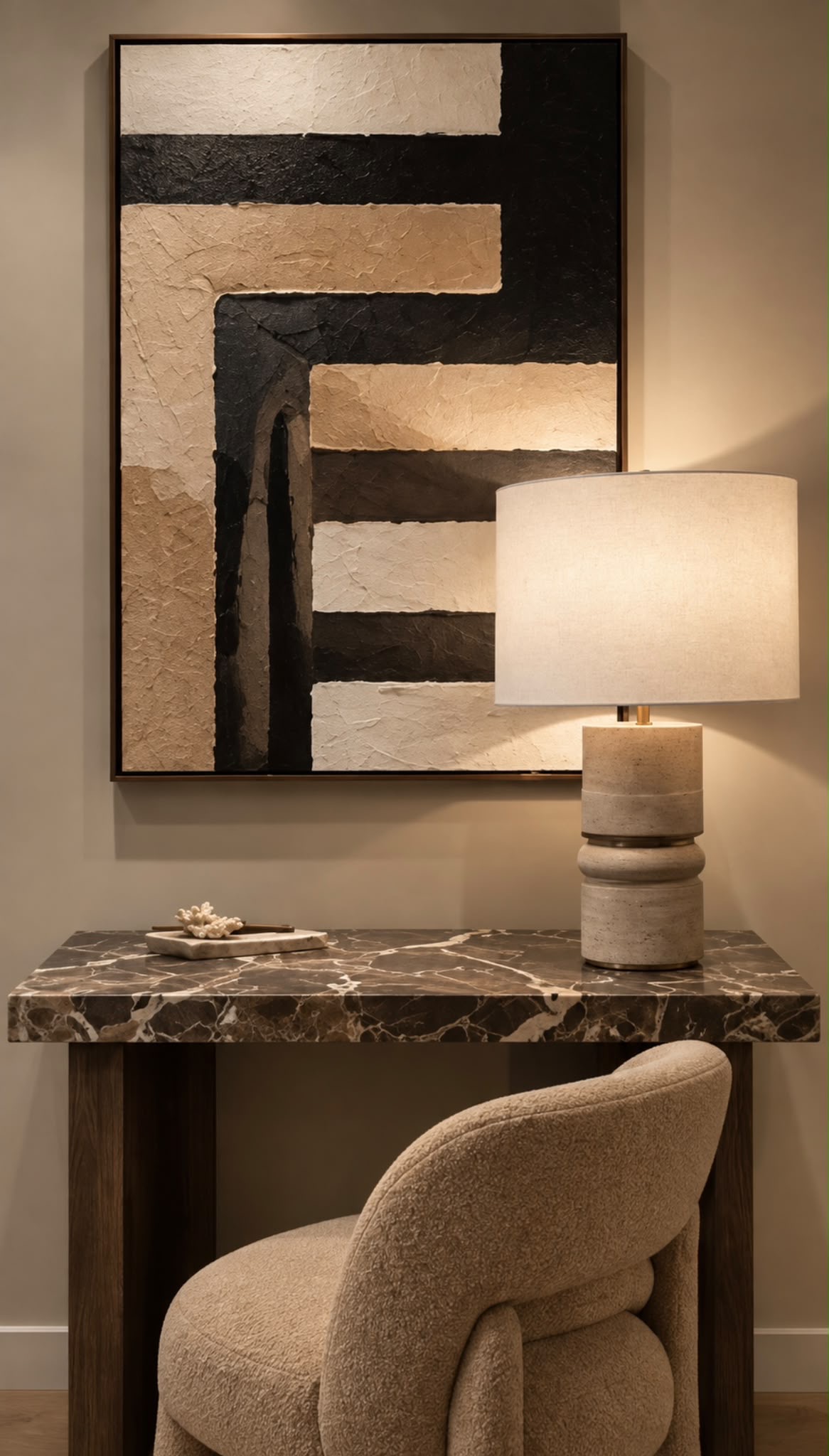Brown veined marble console on dark timber supports, a cream upholstered chair and a stone table lamp beneath textured abstract art by Maison Quari Vera